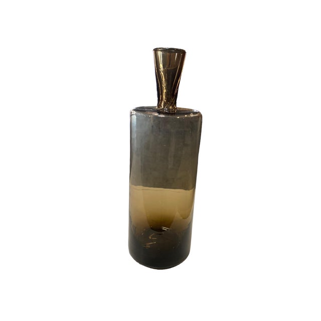 Large smokey glass bottle has a minimalist and modern design, with a sleek, smooth texture. It could serve as a decorative...