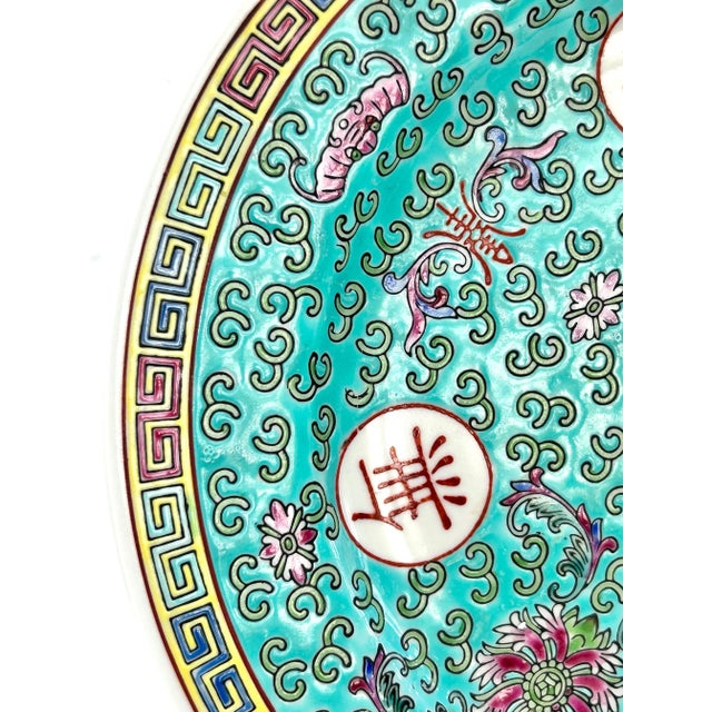 A vibrant 1970s Chinese Mun Shou longevity plate decorated in turquoise, famille rose enamels, floral motifs, and...