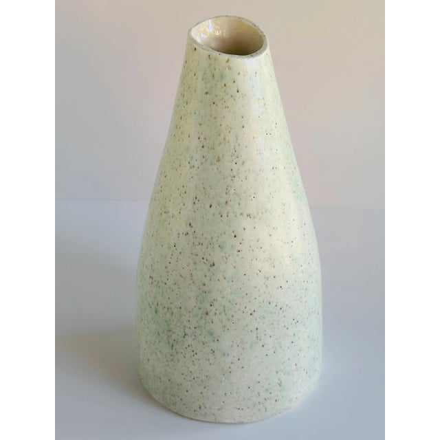 Jug-shaped vase with a buttercream & seafoam green speckled finish. The angled rim exposes its glossy cream-white...
