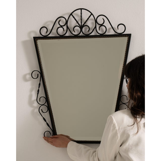 A narrow vertical mirror framed in wrought iron, offering a clean and understated presence. The elongated shape enhances...