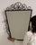 A narrow vertical mirror framed in wrought iron, offering a clean and understated presence. The elongated shape enhances...