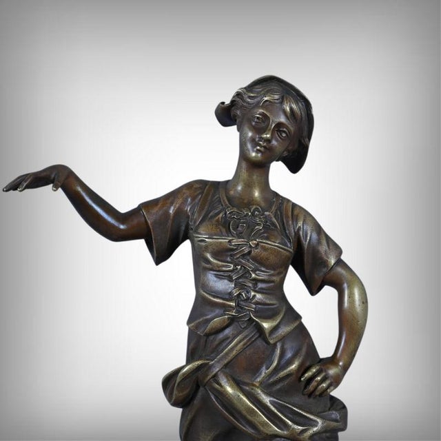 Elegant and poetic, this bronze sculpture with a brown patina depicts a young fisherwoman in a graceful pose, captured in...