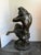 A large-scale patinated bronze depicting a bearded satyr seated on a naturalistic rocky base, head thrown back with one...
