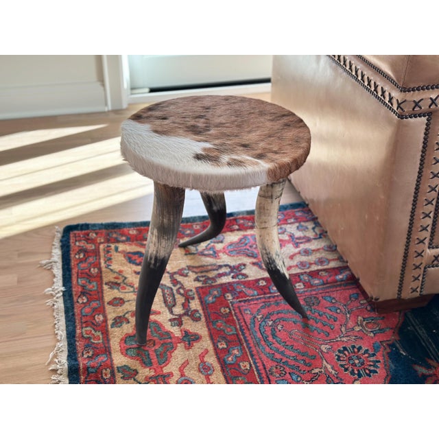 Make a statement in your western home design with this chic vintage side table made of a cowhide upholstered top and bull...