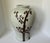 A large hand-painted porcelain jar. Featuring a striking, earthy "rusty brown" twisted tree and weeping plum motif, the...