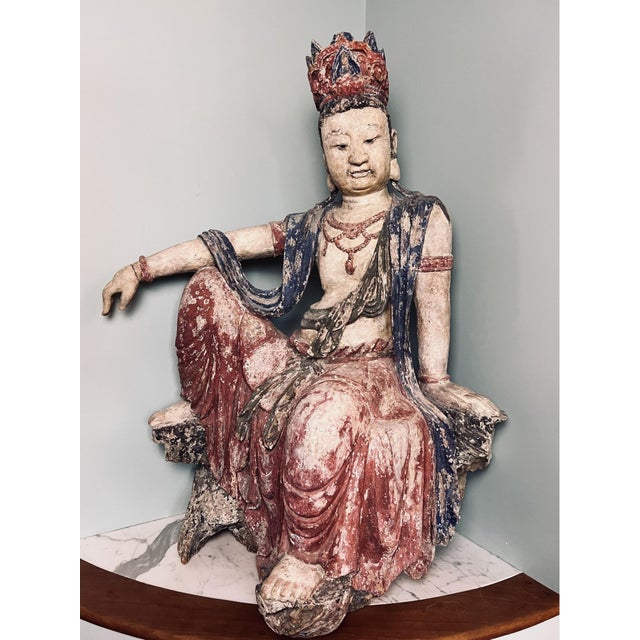 A large antique Chinese polychrome wooden sculpture depicting a seated bodhisattva (likely Guanyin) in a relaxed royal...