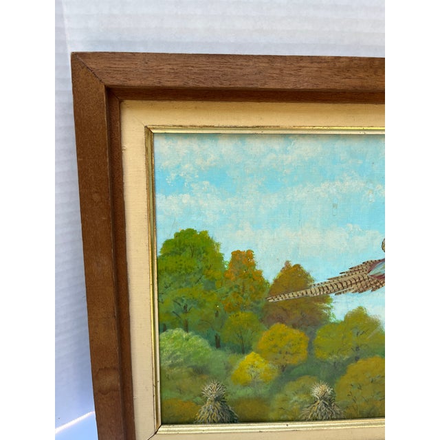 An original acrylic on canvas amateur style painting of a pheasant flying over an outdoor landscape. Finished with a wood...