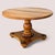 A vintage round solid-maple pedestal table with a turned central column, a shaped quadriform base, and four dark...