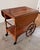 A beautifully crafted mid-century beauty featuring drop-leaf sides, wooden back wheels, and a two-tiered lower storage...