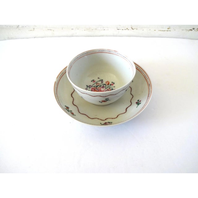 An antique Chinese Export Porcelain teacup and saucer set, hand-painted with flower baskets and floral springs, with rust...