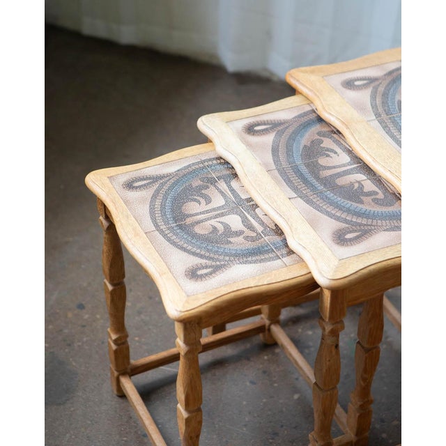 A set of three Danish oak and tile nesting tables designed by Henning Kjærnulf and tiles by Edmund Pedersen — a pairing...