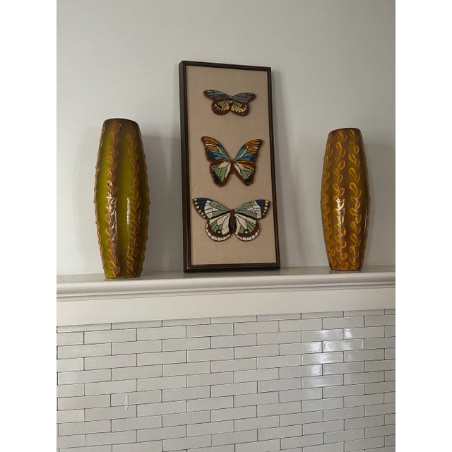 This framed artwork captures the essence of 1960s design with three hand-painted ceramic butterflies in vibrant colors,...
