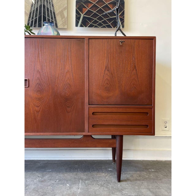 A standout Danish modern teak sideboard by Ejvind A. Johansson, designed to anchor a space with warmth and presence. Rich...