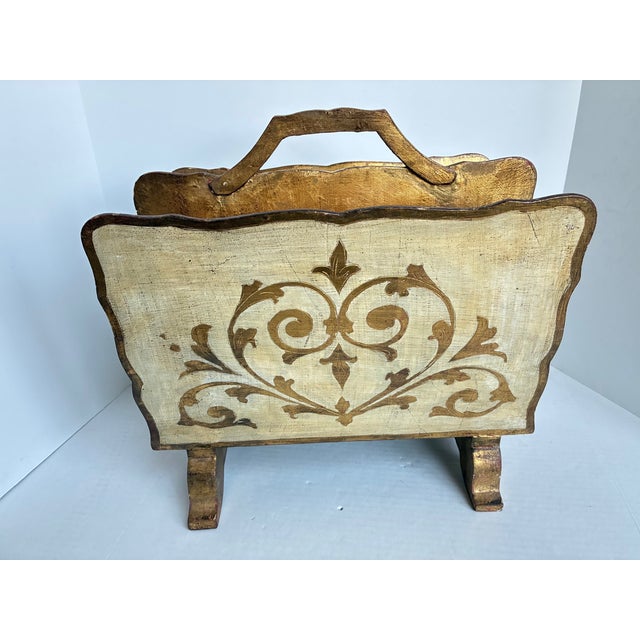 Vintage Italian Florentine magazine rack crafted from wood with an ornate hand-painted gold gilt finish. Features...