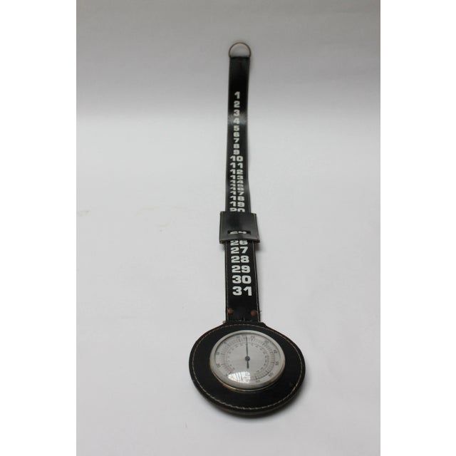Vintage wall-hanging "strap" calendar with moveable leather "slide" to isolate the date and circular disc thermometer...