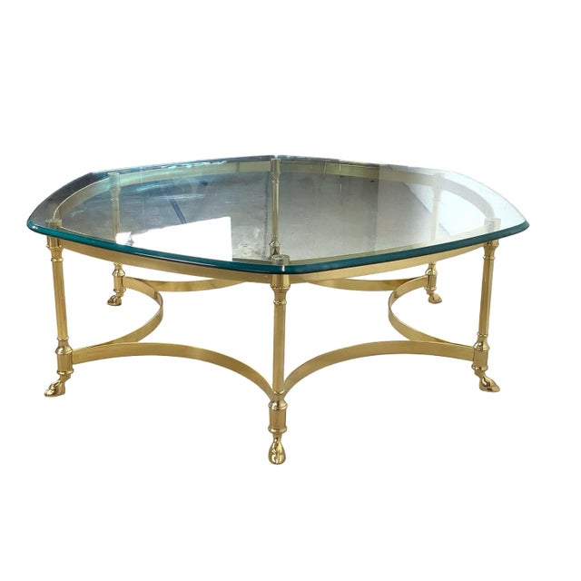 This coffee table channels Hollywood Regency glamour with its shaped beveled glass top resting atop an ornate brass base,...