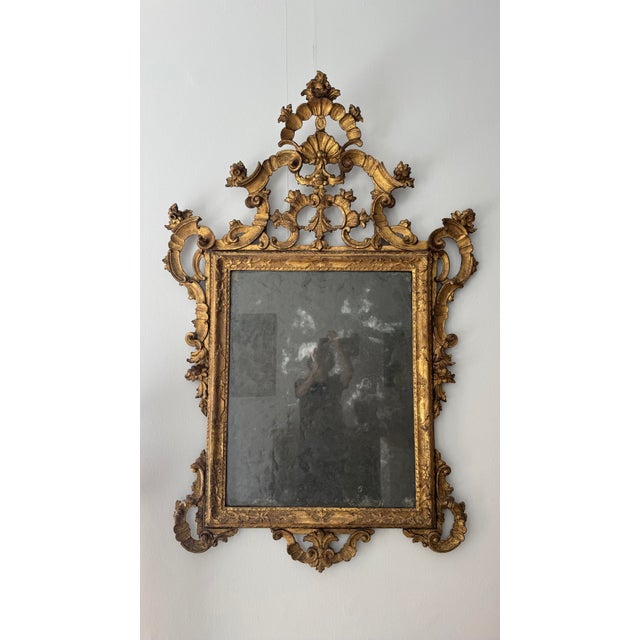 18th-century Venetian gilded wood mirror. This Rococo mirror features an imposing frame in finely carved and gilded wood...