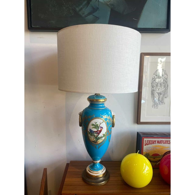 French Sèvres-style porcelain table lamp with a vibrant turquoise blue body, hand-painted bird motif, and fine gilt...