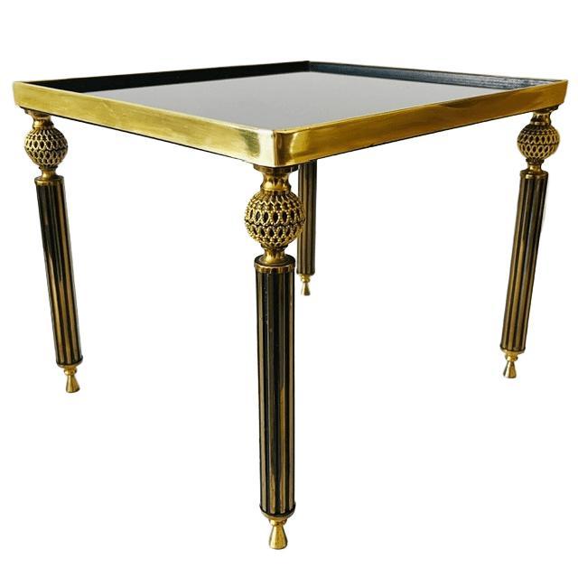 Vintage brass side table with black smoked glass in Hollywood Regency style from the 1960s. The table features beautifully...
