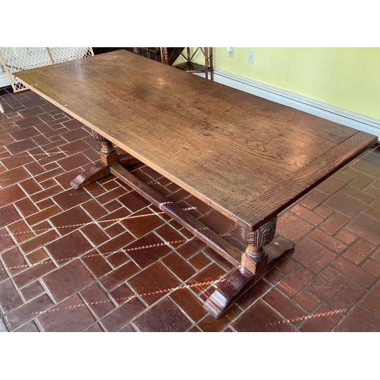 A substantial oak refectory-style dining or library table with a solid plank top with rich, natural grain patterns,...