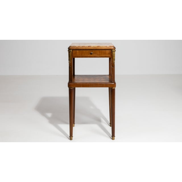 A refined Louis XVI style side table featuring clean neoclassical lines and elegant proportions. The marble top adds...