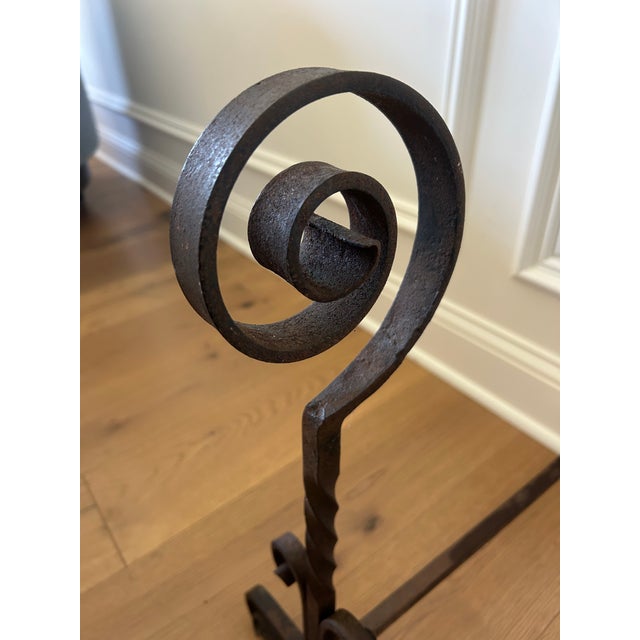 A handsome pair of antique 19th-century wrought iron andirons, showcasing the timeless craftsmanship of traditional...