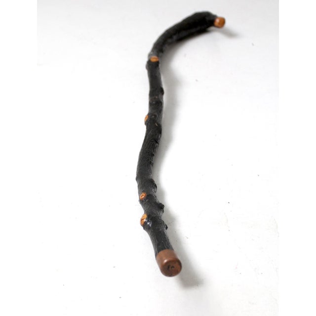 A timeless vintage walking stick crafted from a natural wood branch. The cane's dark tone and organic shape make it a...