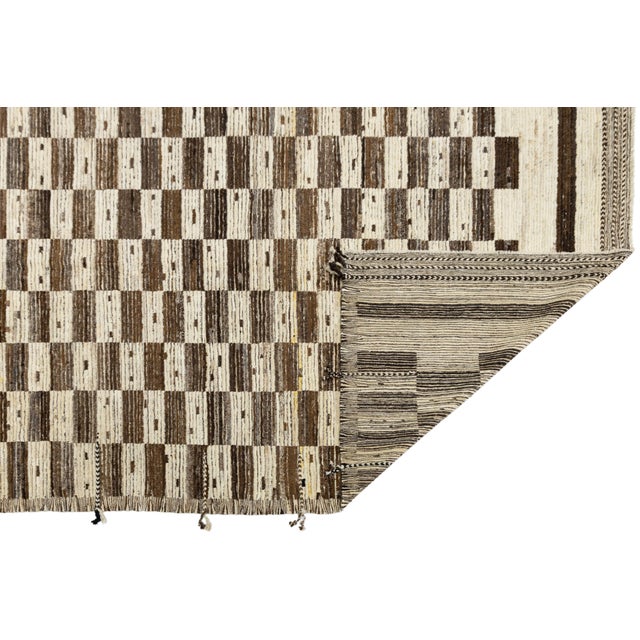 This exquisite rug is a contemporary take on the timeless tribal motifs, featuring a bold, graphic checkerboard or grid...