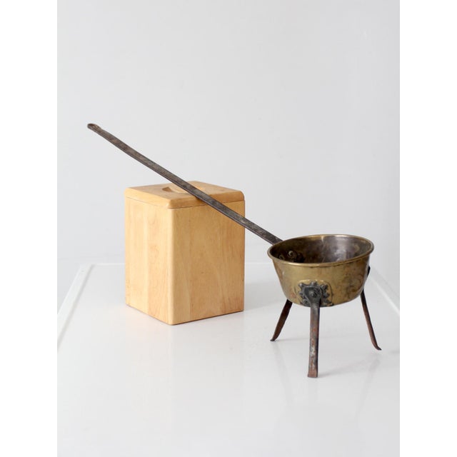 Distinctive antique hearth pan with a deep rounded brass bowl, forged three-legged iron base, and unusually long...