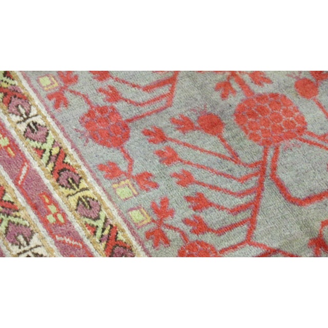 A full pile excellent condition early 20th century Khotan rug. Gray ground, pinky red accent pomegranates throughout with...