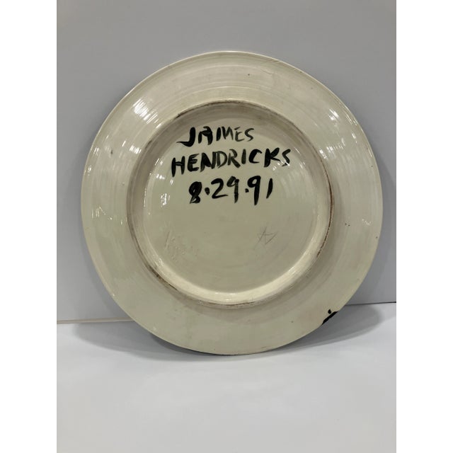 This hand painted charger is signed James Hendricks (1938-2017) His work is in the collections of : The Smithsonian...
