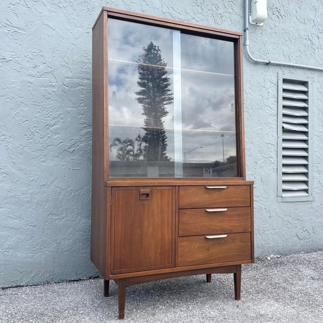 A refined Mid-Century Modern display cabinet by Stanley Furniture, showcasing the timeless appeal of clean lines and warm...