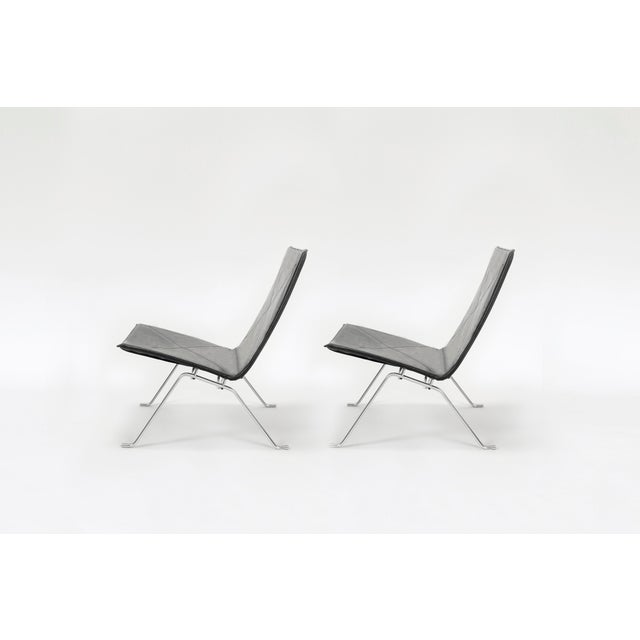 Set of two PK22 lounge chairs designed by Poul Kjærholm and manufactured by Fritz Hansen. Featuring black leather seats...