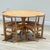 A refined mid-century dining set comprising a circular elm table and four matching rattan chairs, preserved in its...
