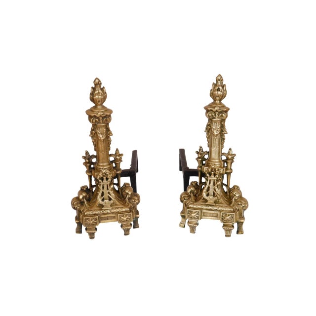 A pair of Regency style andirons by United Manufacturing. Brass and iron andirons are decorated with musical details....