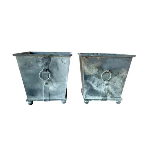 Pair of Neoclassical Metal Planters. Crafted in a tapering square form, each planter features a weathered gray patina that...