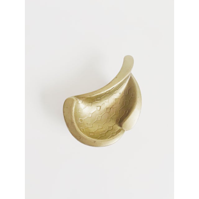 A small yet heavy cast brass dish with geometric carved details.