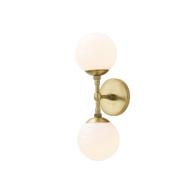 A perfect balance of proportions, this double sconce sets frosted glass globes against antique brass arms and back plate....
