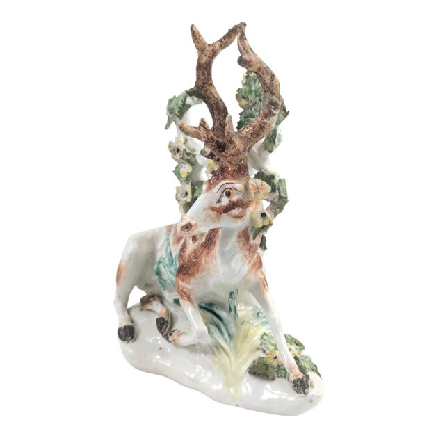 A mid-18th century Derby porcelain figure of a recumbent stag, modelled before a flowering bocage tree. The piece reflects...