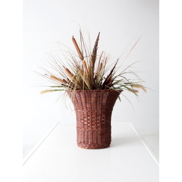 This vintage wicker basket features a tall, slender shape and gently fluted top. Ideal for tabletop display or as a...