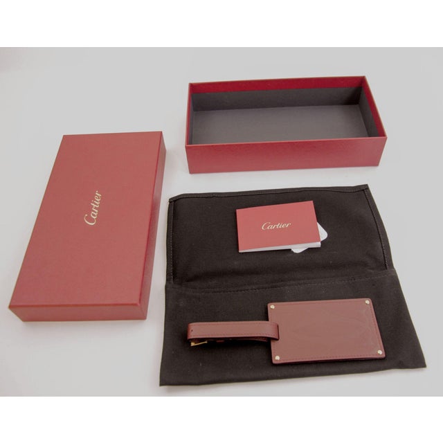 The Cartier Paris burgundy calfskin leather luggage tag is as stylish as it is practical with gold-finished metal corners...