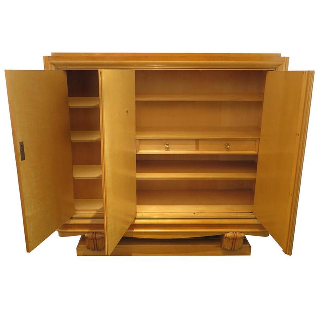 French Art Deco grande Sycamore cabinet with floral bas relief detail in gold leaf. The cabinet doors showcase a parquetry...