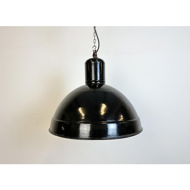 Industrial factory hanging lamp made in former Czechoslovakia during the 1950s. It features a black enamel shade with...