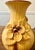 This vase is characterized by its rich mustard yellow/tan body with a prominent ribbed texture, accented by darker brown...