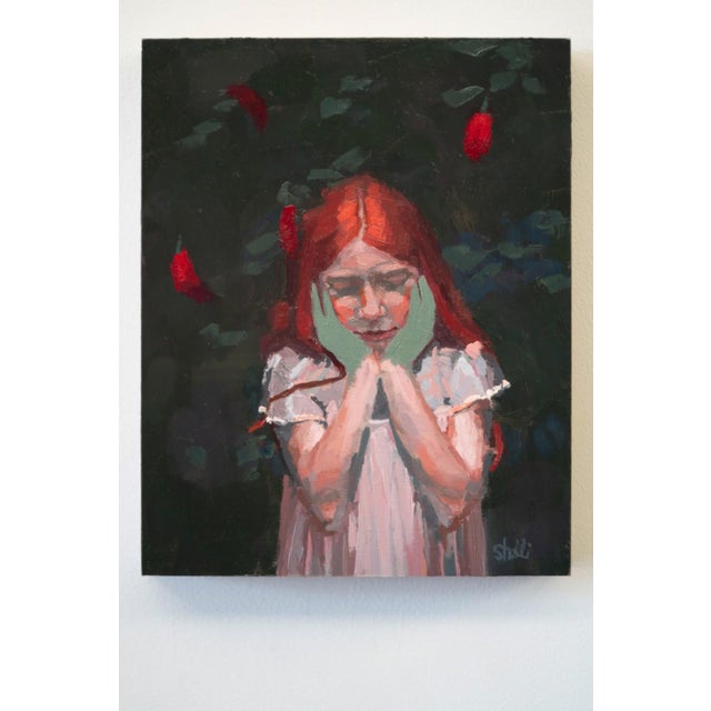 In "Girl with Peppers," a young girl with flowing red hair stands amidst a dark, leafy background, her hands gently...