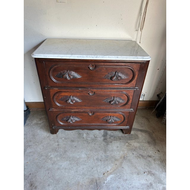 Beautiful small scale chest of drawers with marble top. The handles have a carved botanical design.