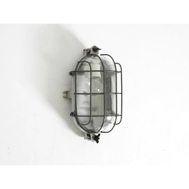 Large, heavy, original mid-century industrial wall or ceiling lamp. Solid cast aluminum frame with a glass shade behind a...