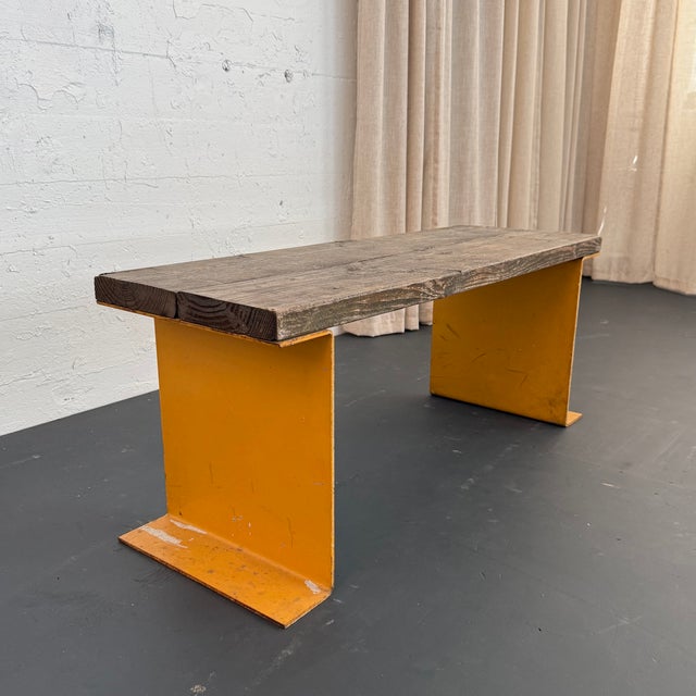 This vintage industrial bench or coffee table pairs a heavy-duty architectural foundation with organic, time-earned...