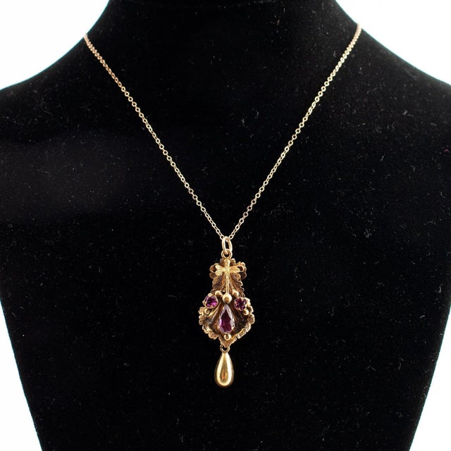 Mid 19th Century This pendant necklace is crafted with 12k and 14k gold. The piece features a central rhodolite stone,...