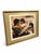 A richly colored figurative reproduction print depicting an intimate domestic scene of a seated mother with two young...